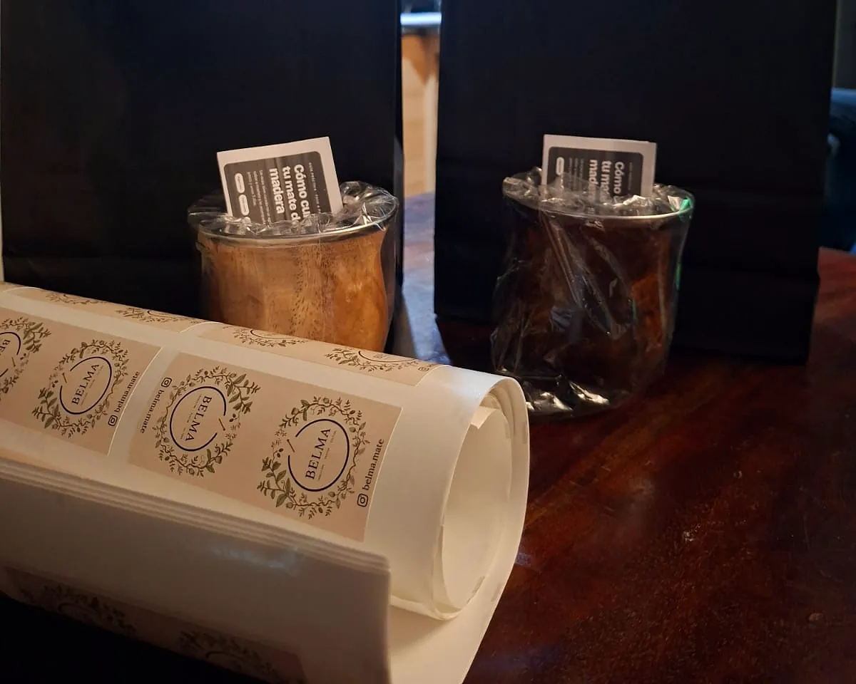 Mates envueltos con tarjeta Belma, bolsas negras y rollo de stickers de la marca